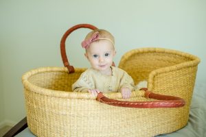 Little girl in a natural color boga moses basket 